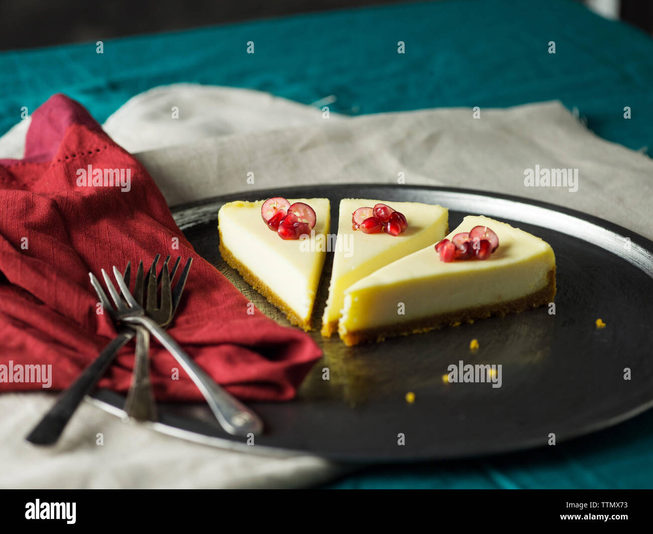 Scheiben von Käsekuchen mit Serviette und Gabeln in die Platte auf dem Tisch Stockfoto