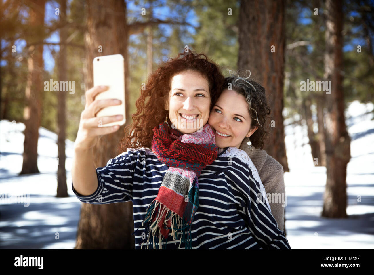 Lächelnd Freunde unter selfie beim Stehen in der Wald im Winter Stockfoto