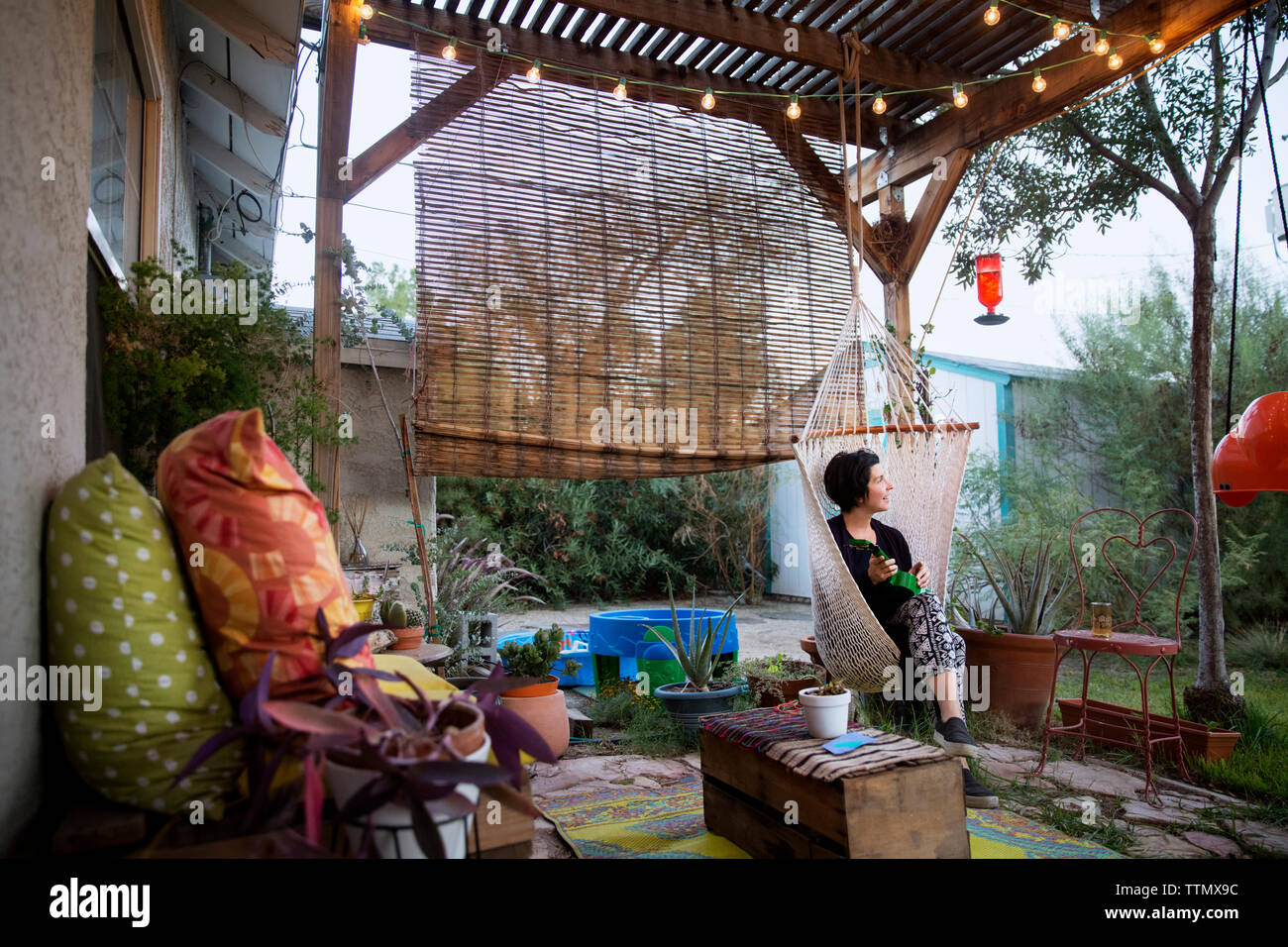 Nachdenkliche Frau sitzt auf der Hängematte Stuhl im Patio Stockfoto