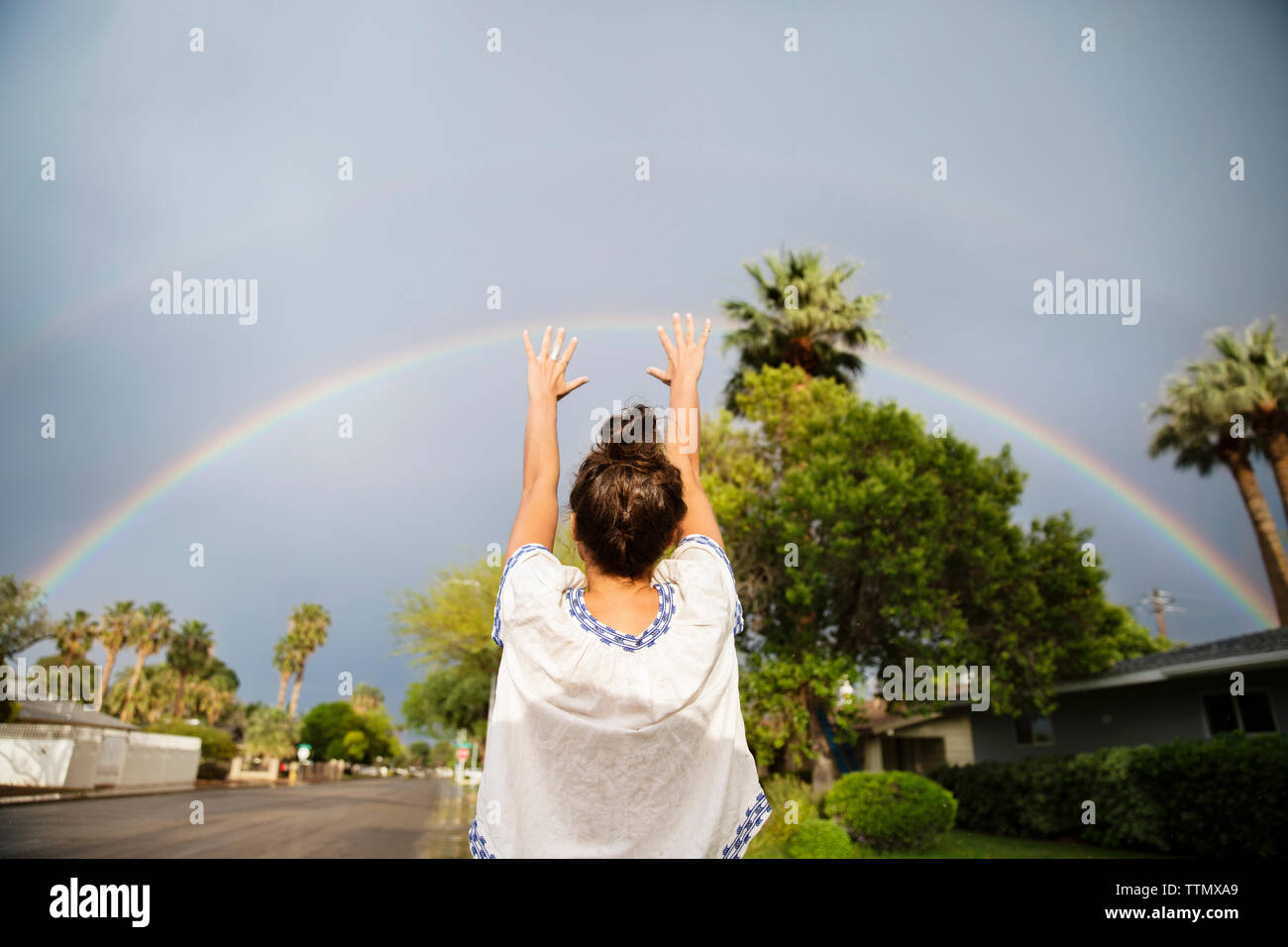 Ansicht der Rückseite Frau deutete auf Regenbogen in der Regenzeit Stockfoto