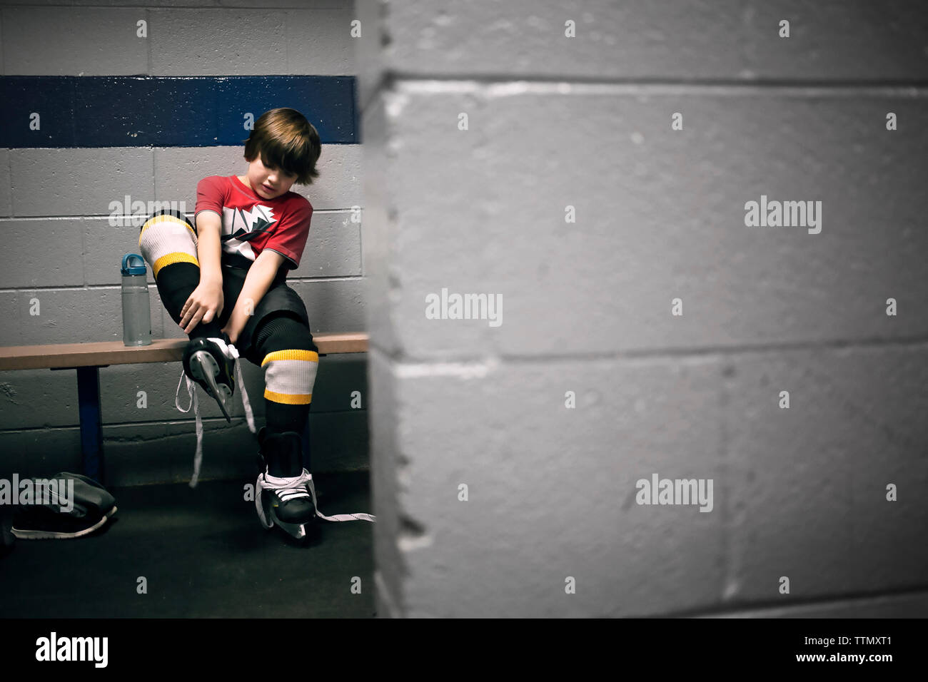 Junge setzen auf Eishockey Schlittschuhe Stockfoto