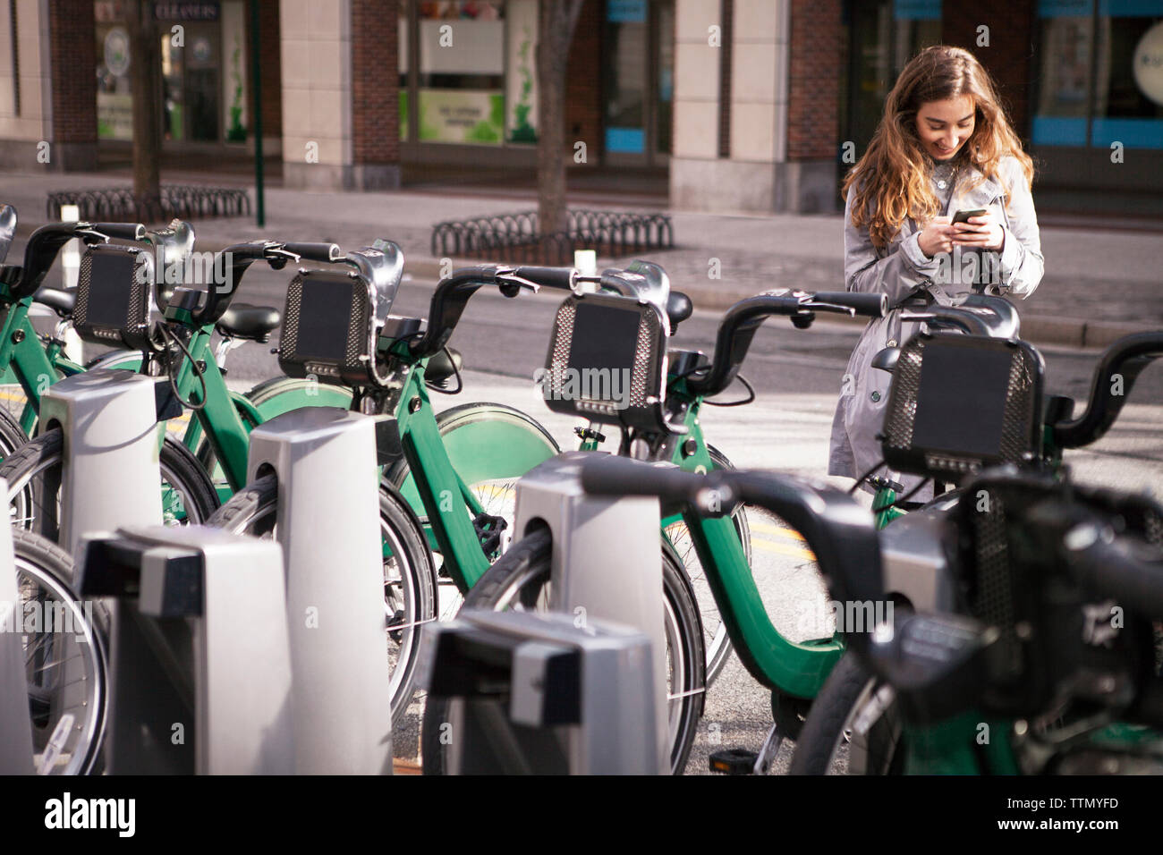 Junge Frau mit Handy von Fahrräder, Parkplatz Stockfoto