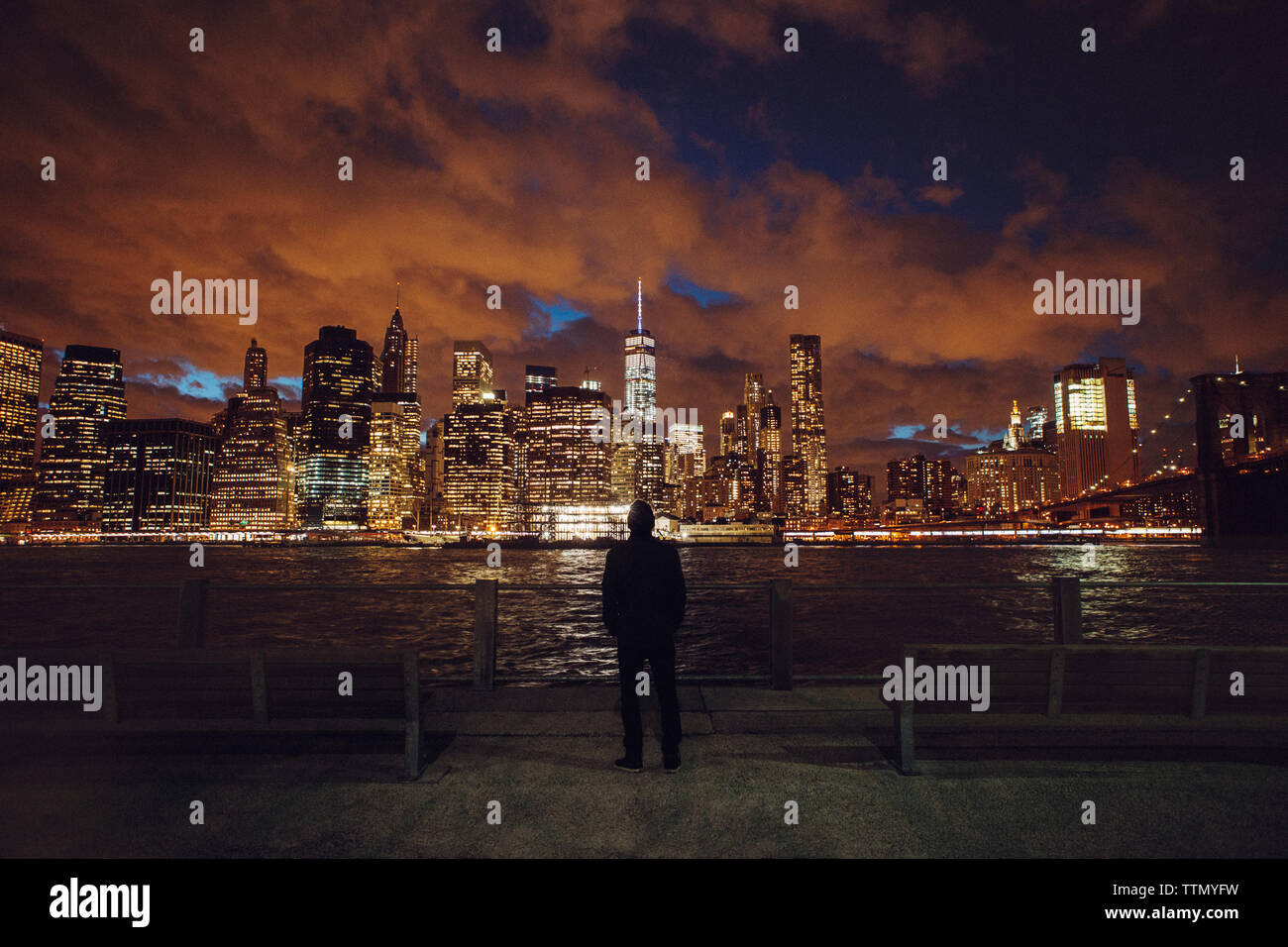 Rückansicht des Menschen auf der Suche nach beleuchtete Skyline bei Nacht Stockfoto