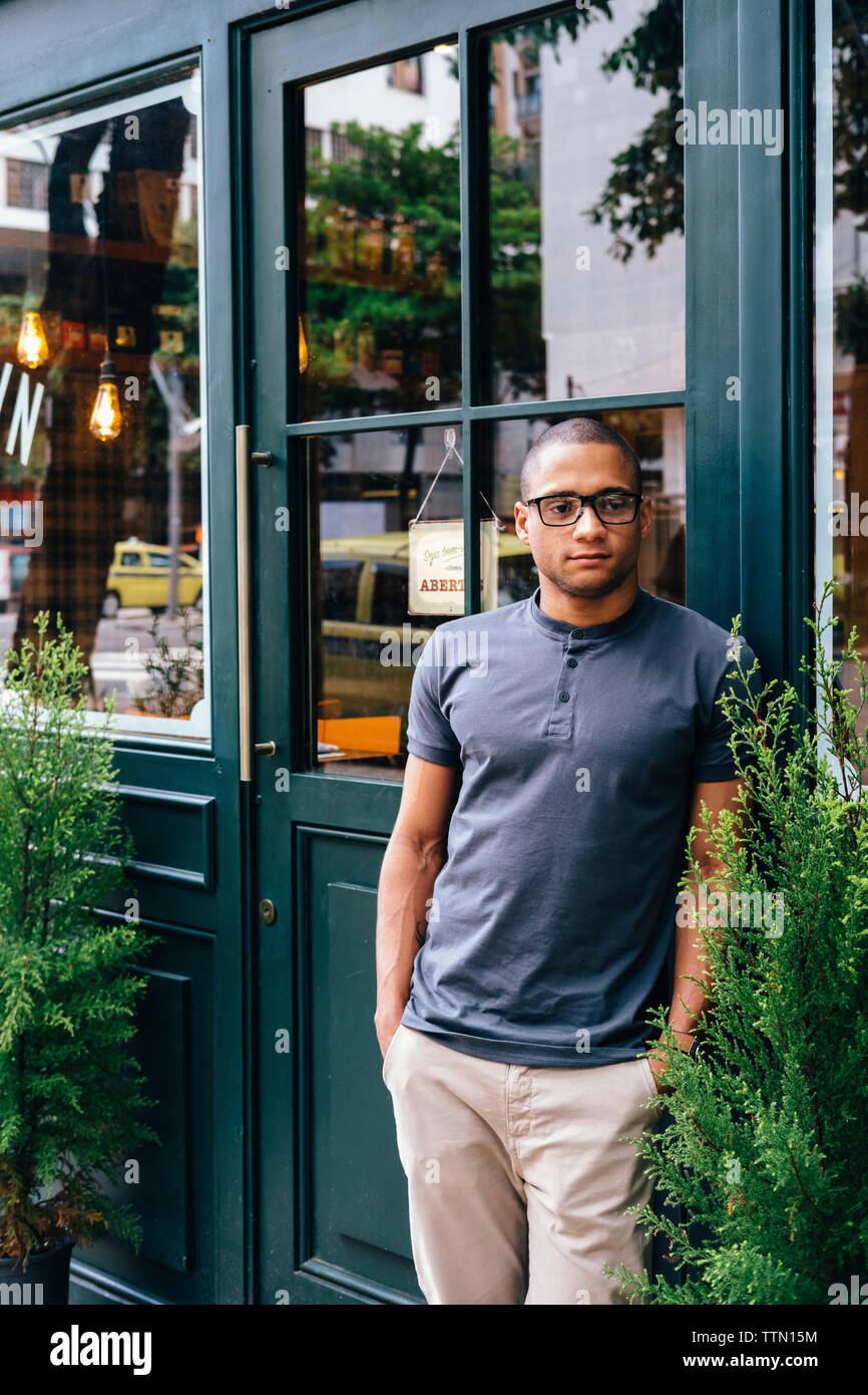 Nachdenklicher junger Mann mit Händen in den Taschen der Weg schauen, während gegen Coffee Shop Stand Stockfoto