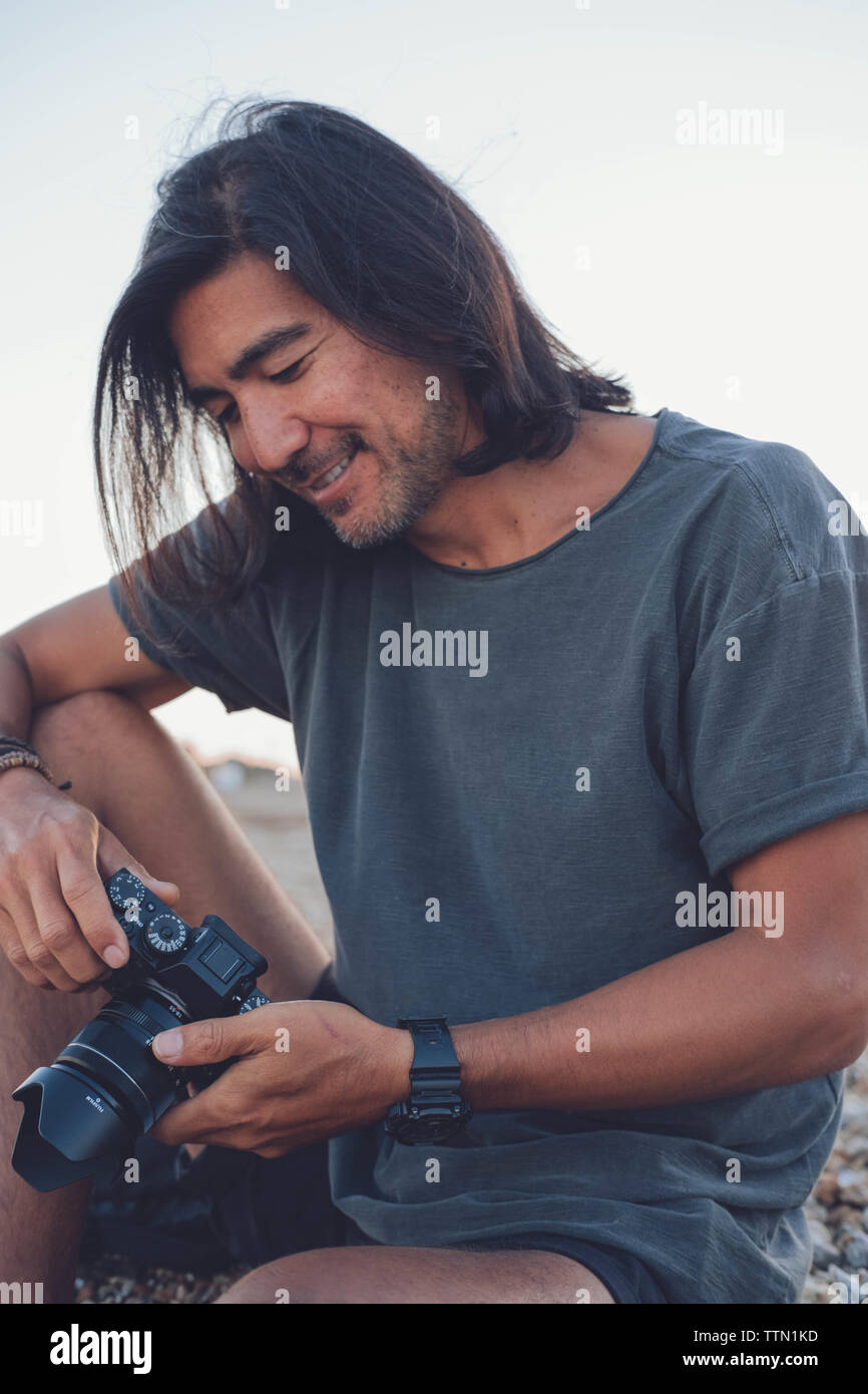 Person lächelnd am Strand, während Sie seine Kamera Stockfoto