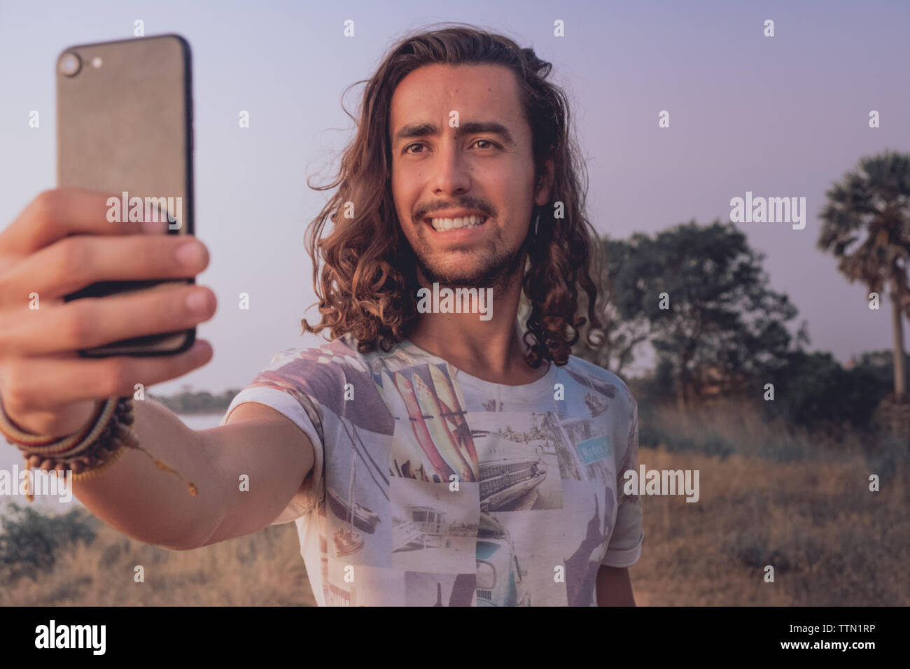 Mann lächelnd, während Sie einen selfie bei Sonnenuntergang im Freien Stockfoto