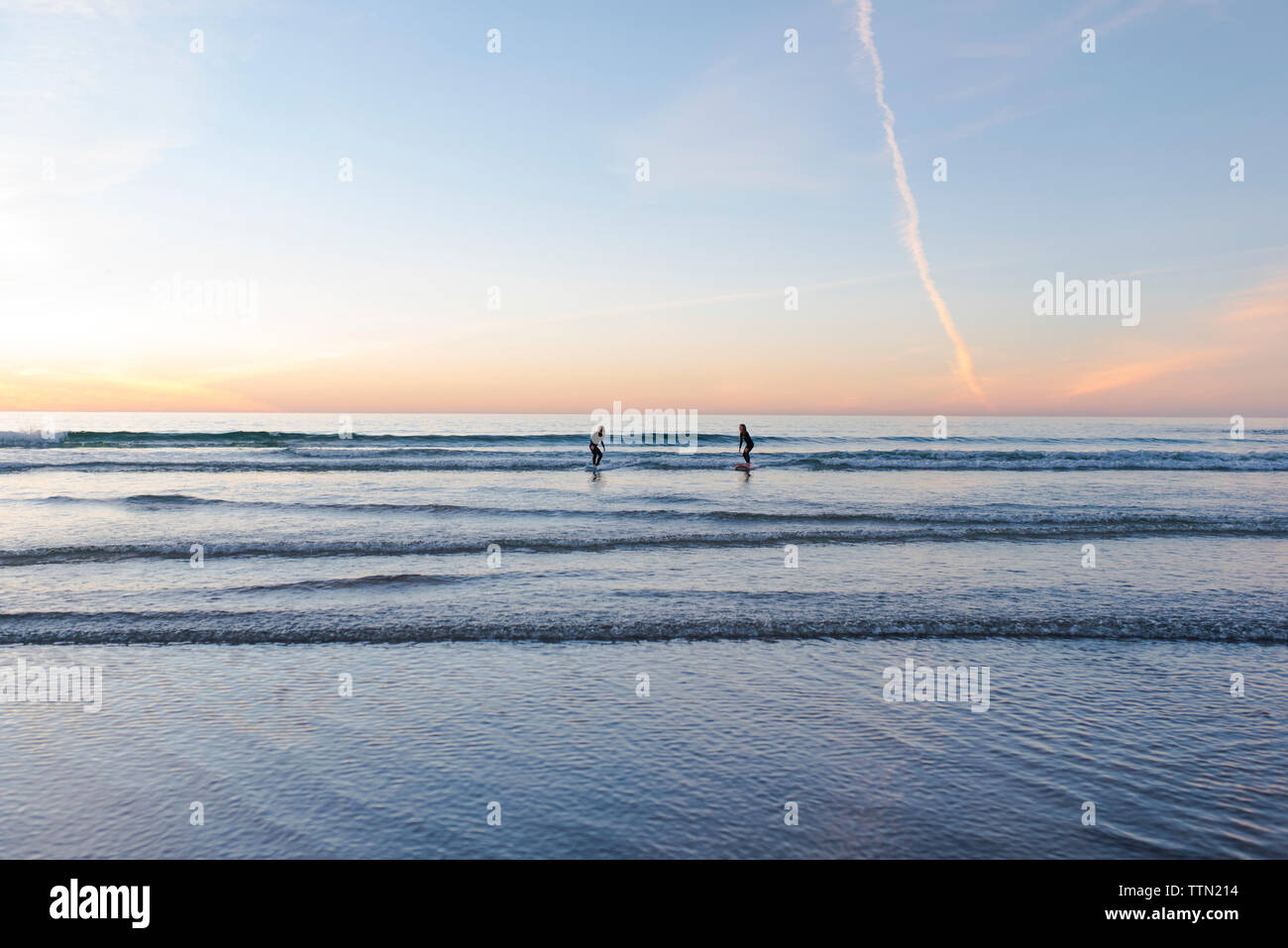 Junge surfer Mädchen fangen eine Welle zusammen bei Sonnenuntergang Stockfoto