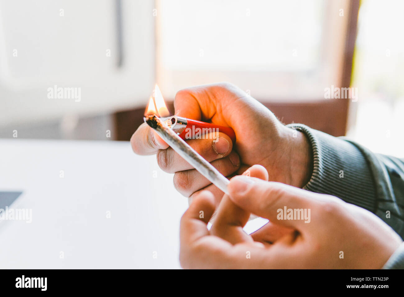 7/8 Hand des Menschen entzünden Marihuana gemeinsame mit Zigarettenanzünder zu Hause Stockfoto