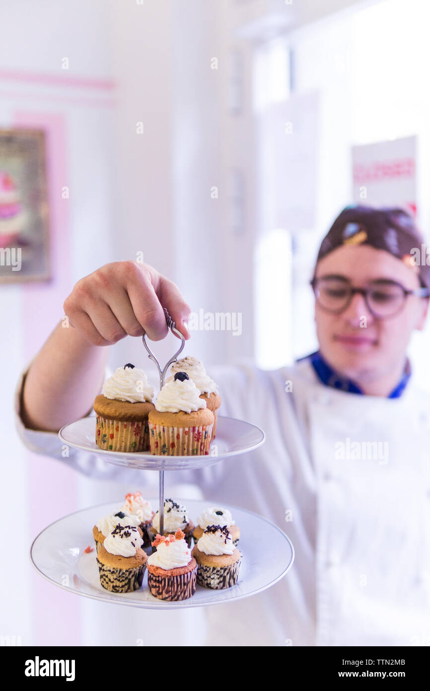 Männliche baker Holding cupcakes im Stand während im Labor stehen Stockfoto