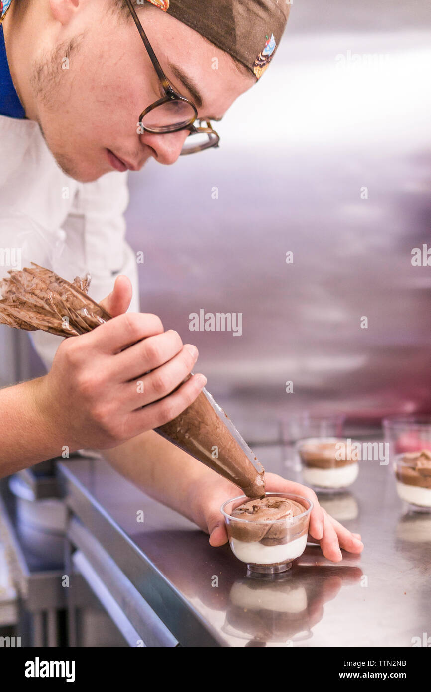 Männliche Baker, Dessert mit Schlagsahne Cremes auf den Küchentisch im Labor Stockfoto