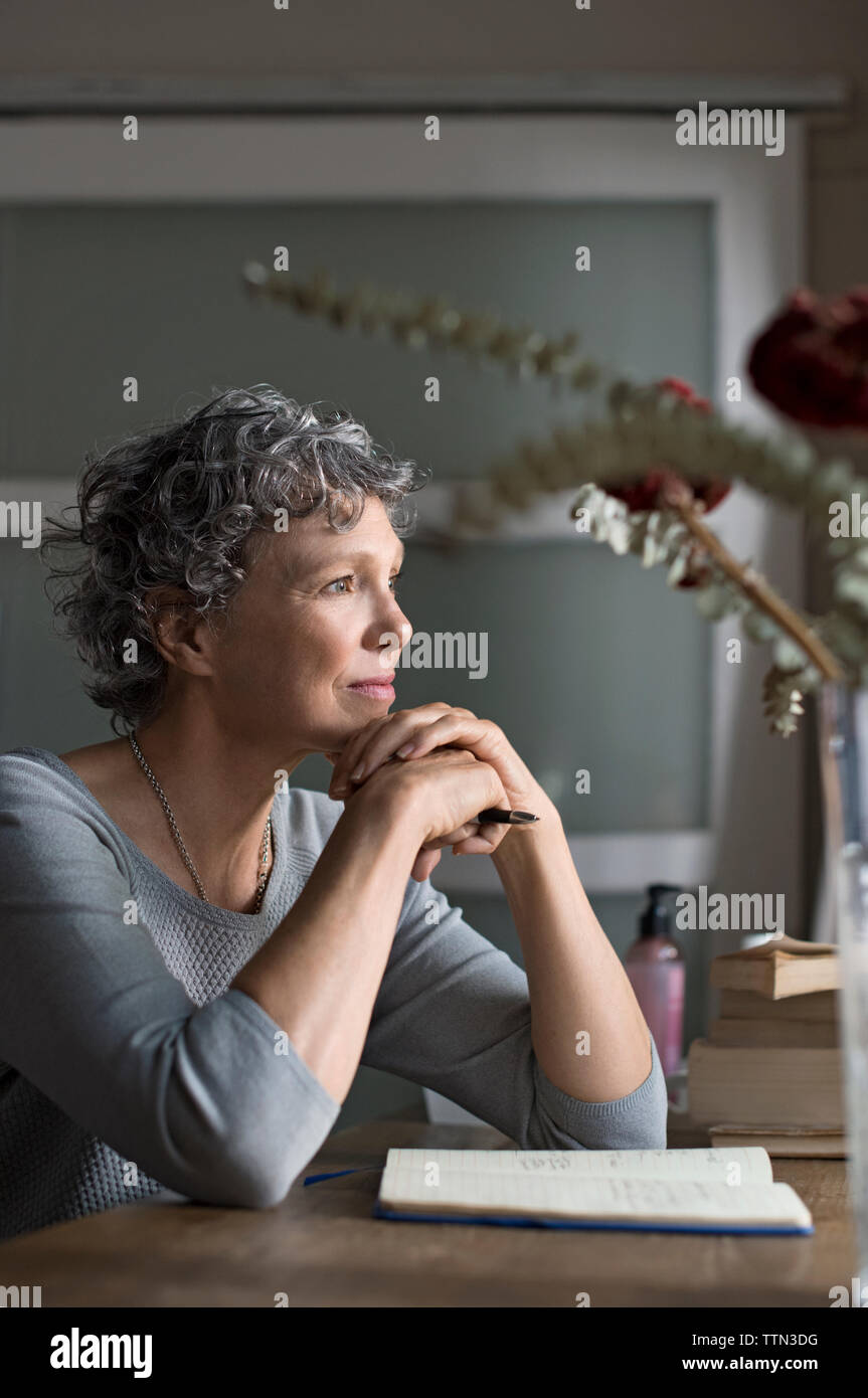 Nachdenklich, reife Frau von Tisch zu Hause sitzen Stockfoto