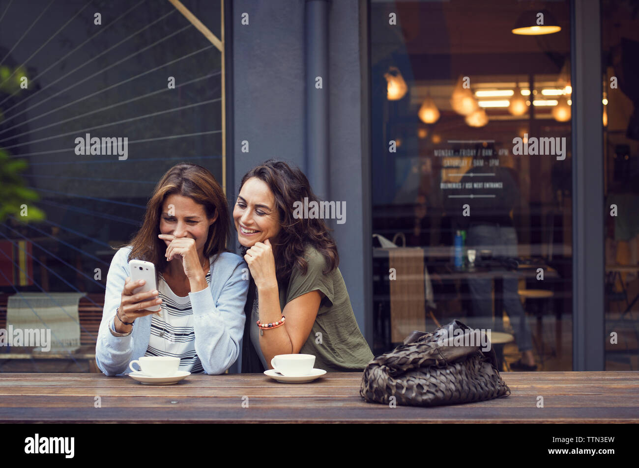 Gerne reife Frauen mit Smart Phone auf Sidewalk Cafe Stockfoto