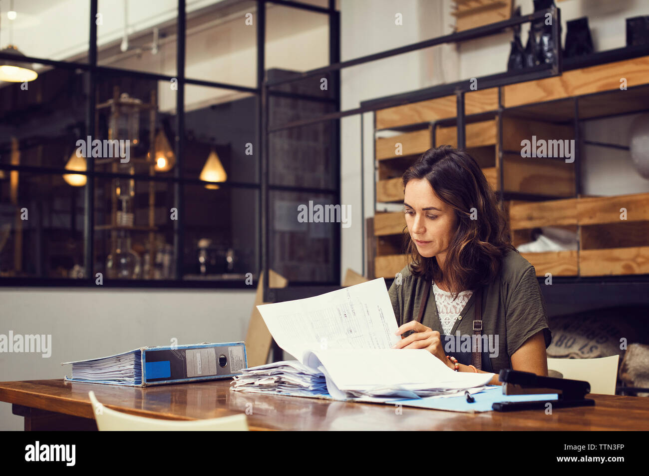 Reife weibliche Besitzer die Analyse von Dokumenten im Coffee Shop Stockfoto