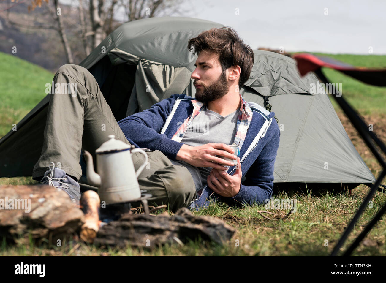 Nachdenkliche Menschen entspannend außerhalb Zelt auf einem Hügel Stockfoto