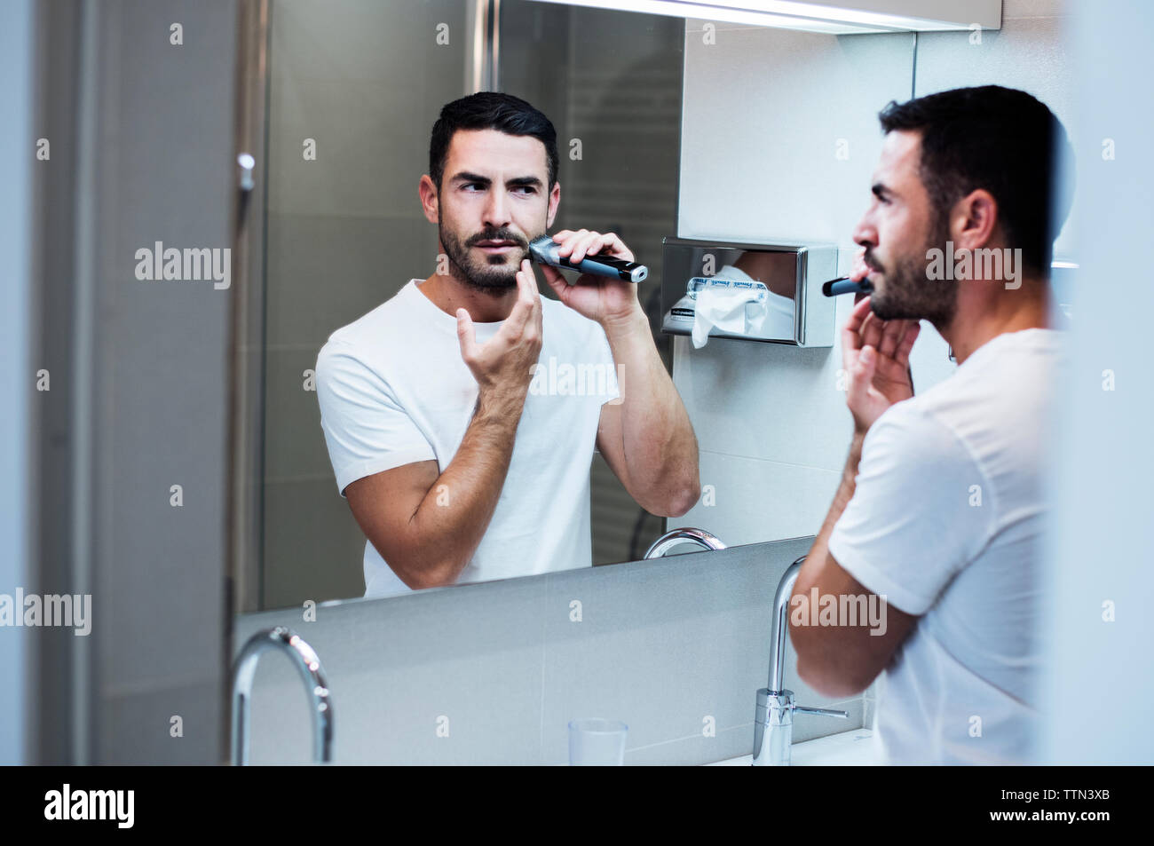 Mann mit elektrischer Rasierer im Badezimmer des Hotels Zimmer Stockfoto