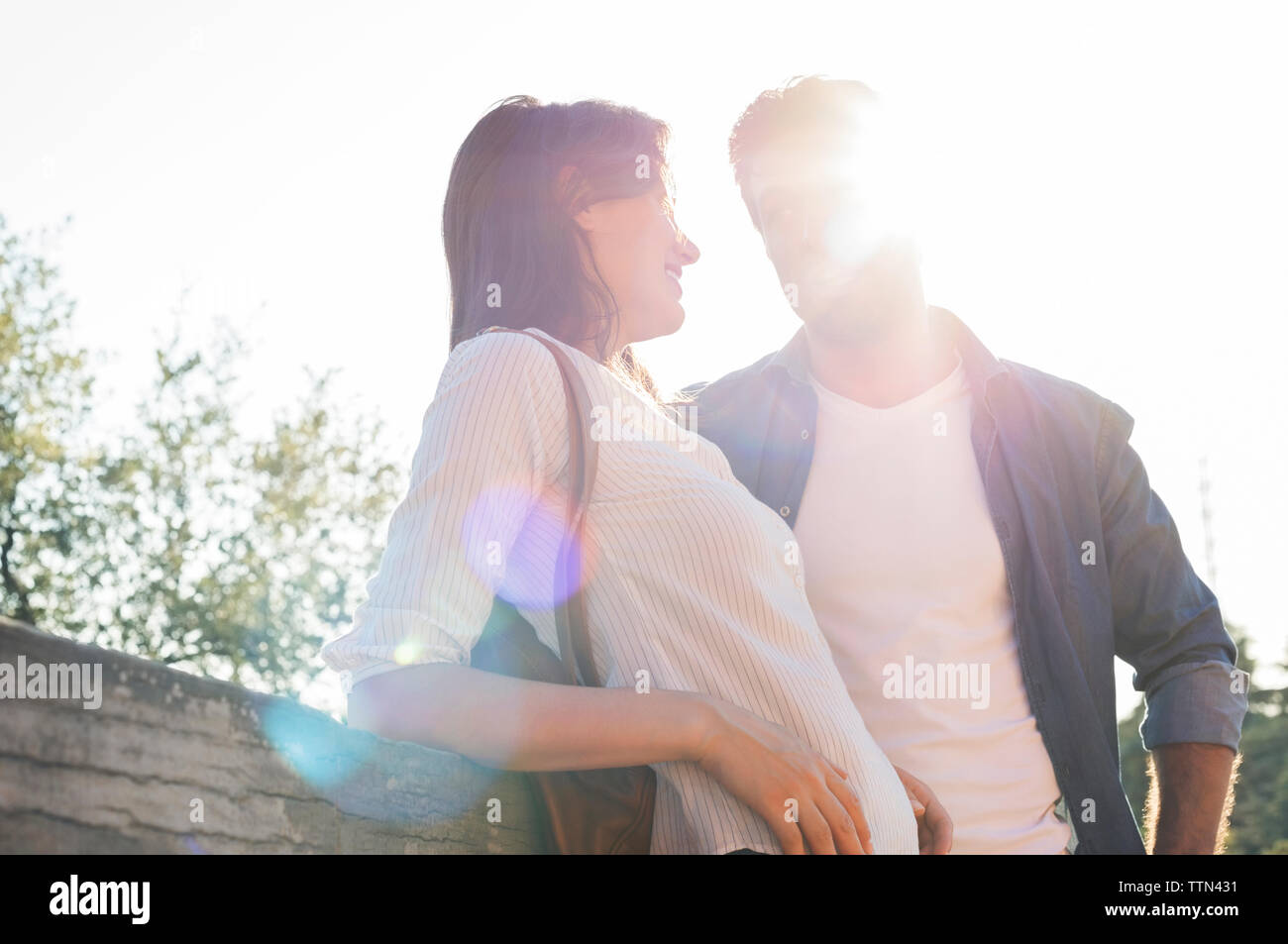 Romantisches Paar stehend durch Geländer an einem sonnigen Tag Stockfoto