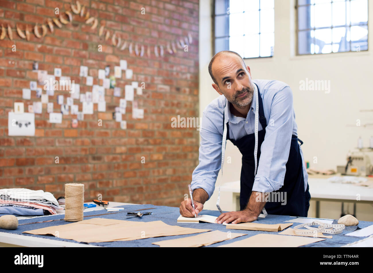 Männliche Fashion Designer weg schauen, während bei Tisch Arbeiten in der Werkstatt Stockfoto