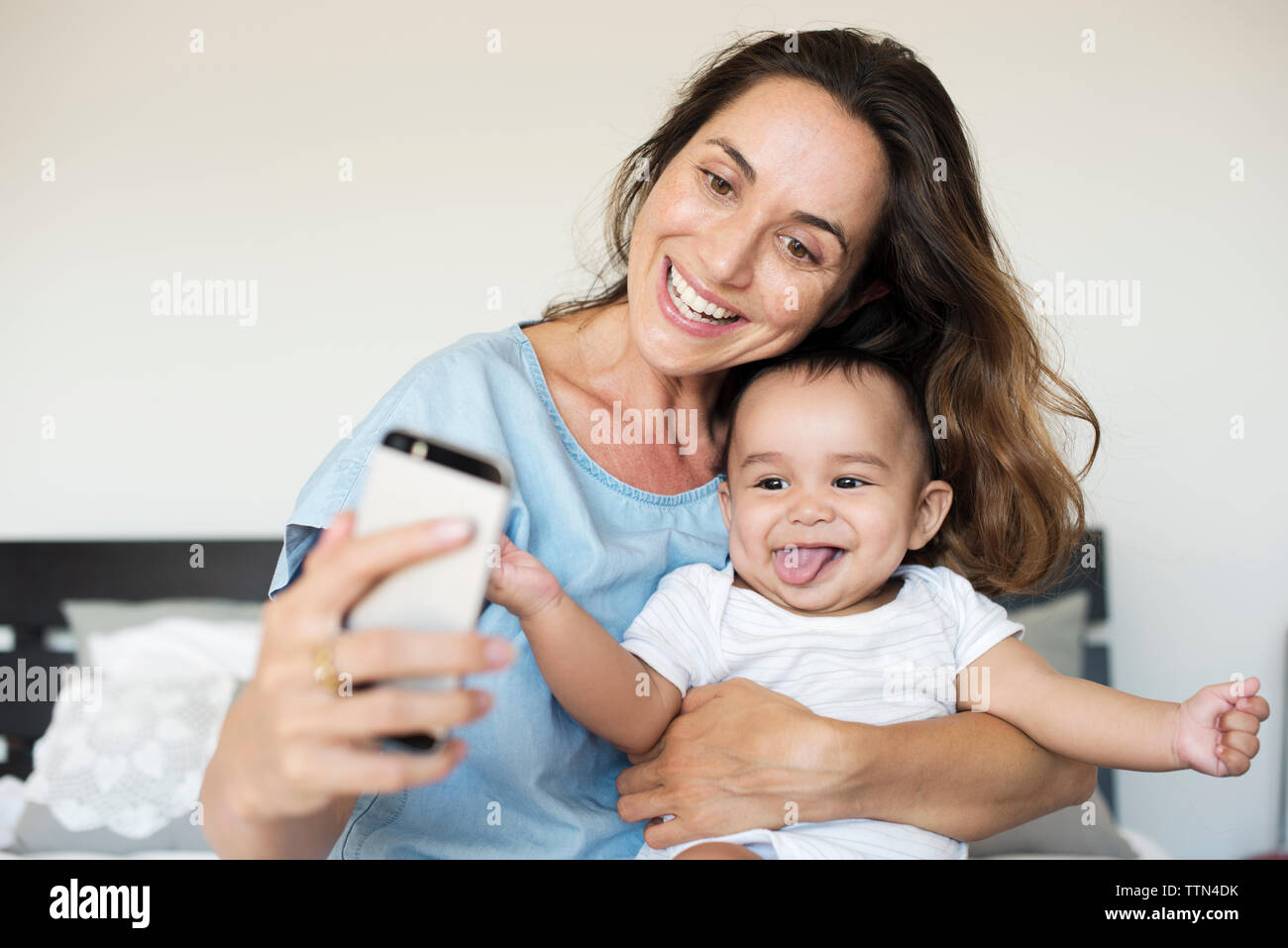 Glückliche Mutter von selfie während mit Sohn auf dem Bett zu Hause sitzen Stockfoto