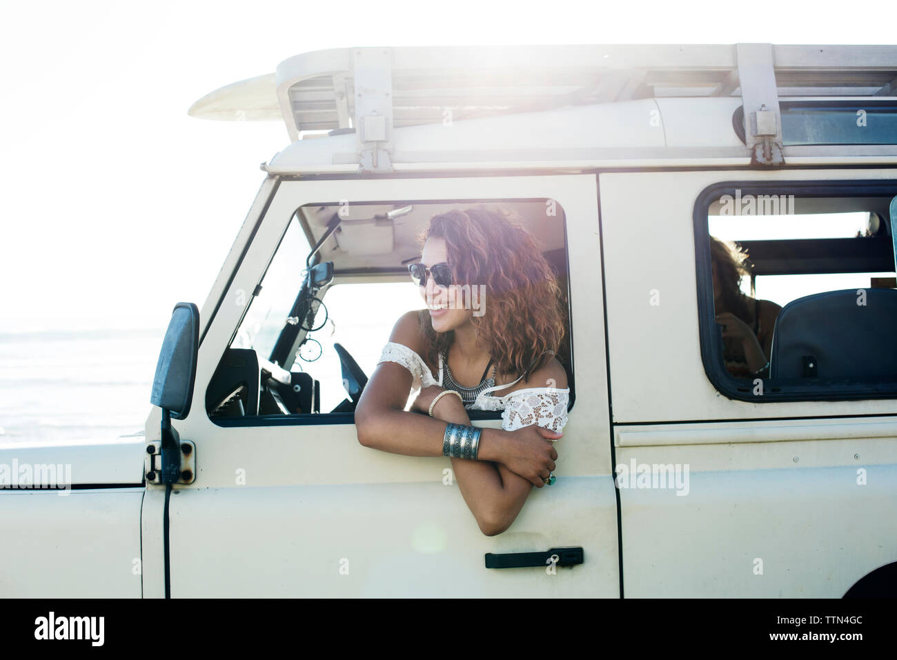 Lächelnde Frau mit Sonnenbrille sitzen in Off-road-Fahrzeug während der sonnigen Tag Stockfoto