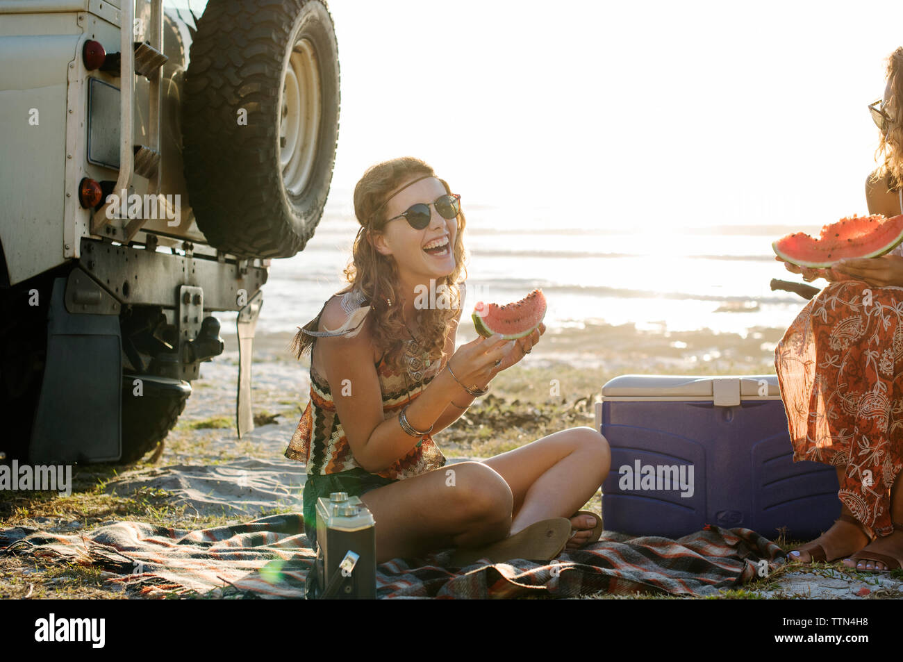 Gerne weibliche Freunde essen Wassermelone am Strand gegen den klaren Himmel Stockfoto