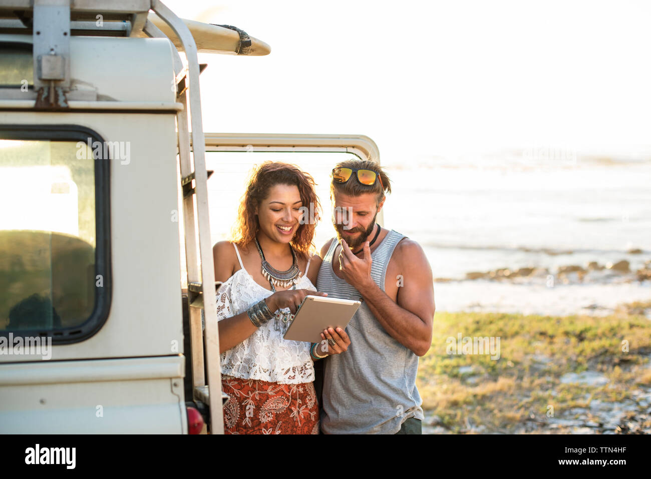 Frau, Tablet Computer Freund während durch Stand-Fahrzeug am Strand Stockfoto