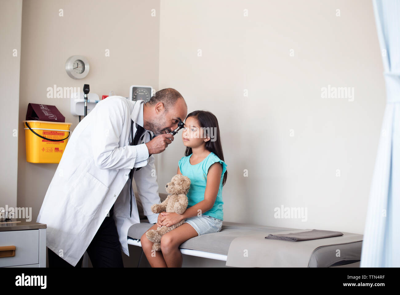 Arzt mit otoskop für Girl's Ohr im Untersuchungsraum Stockfoto
