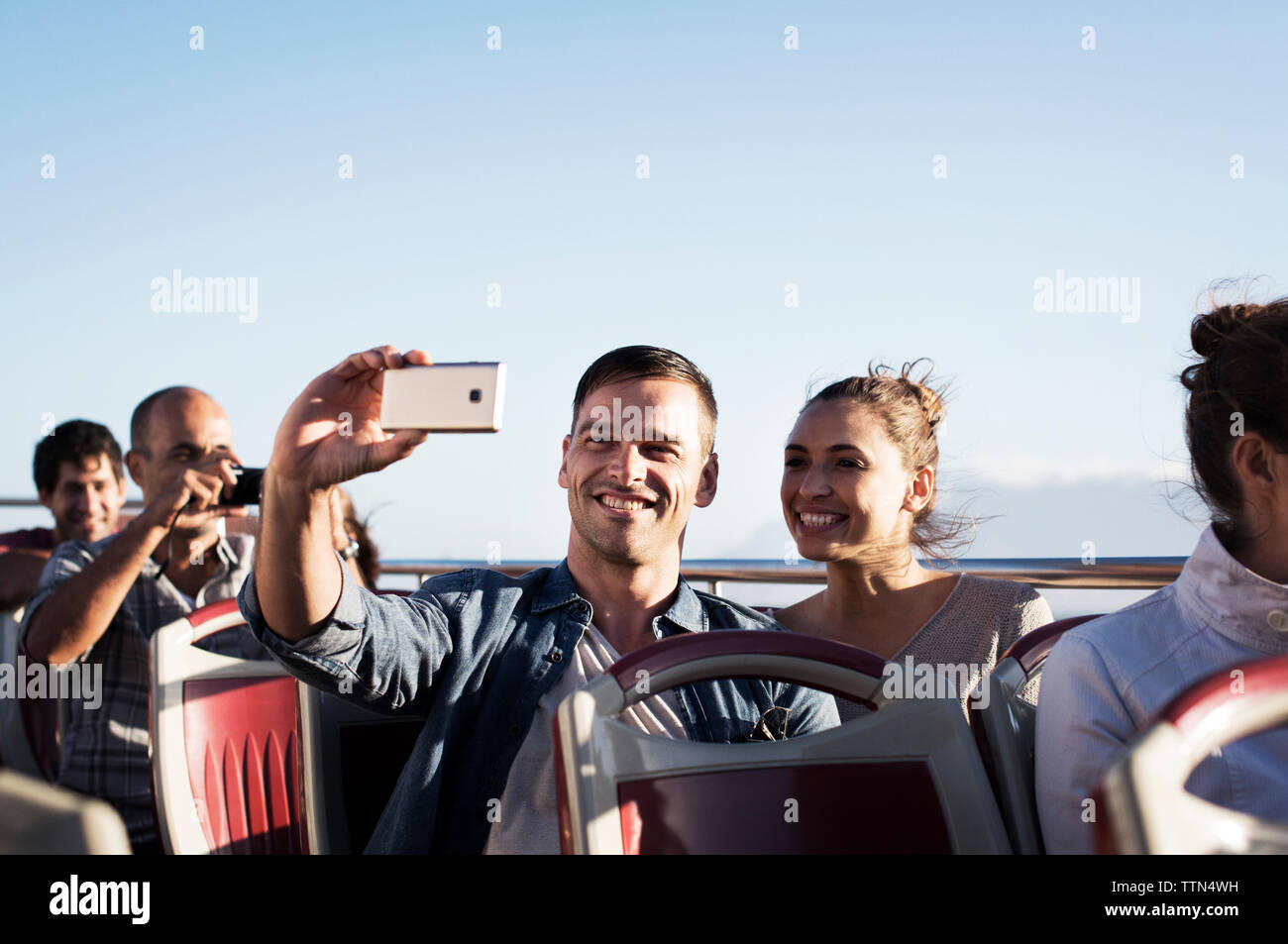 Paar unter selfie während der Fahrt im Doppeldeckerbus gegen den klaren Himmel Stockfoto