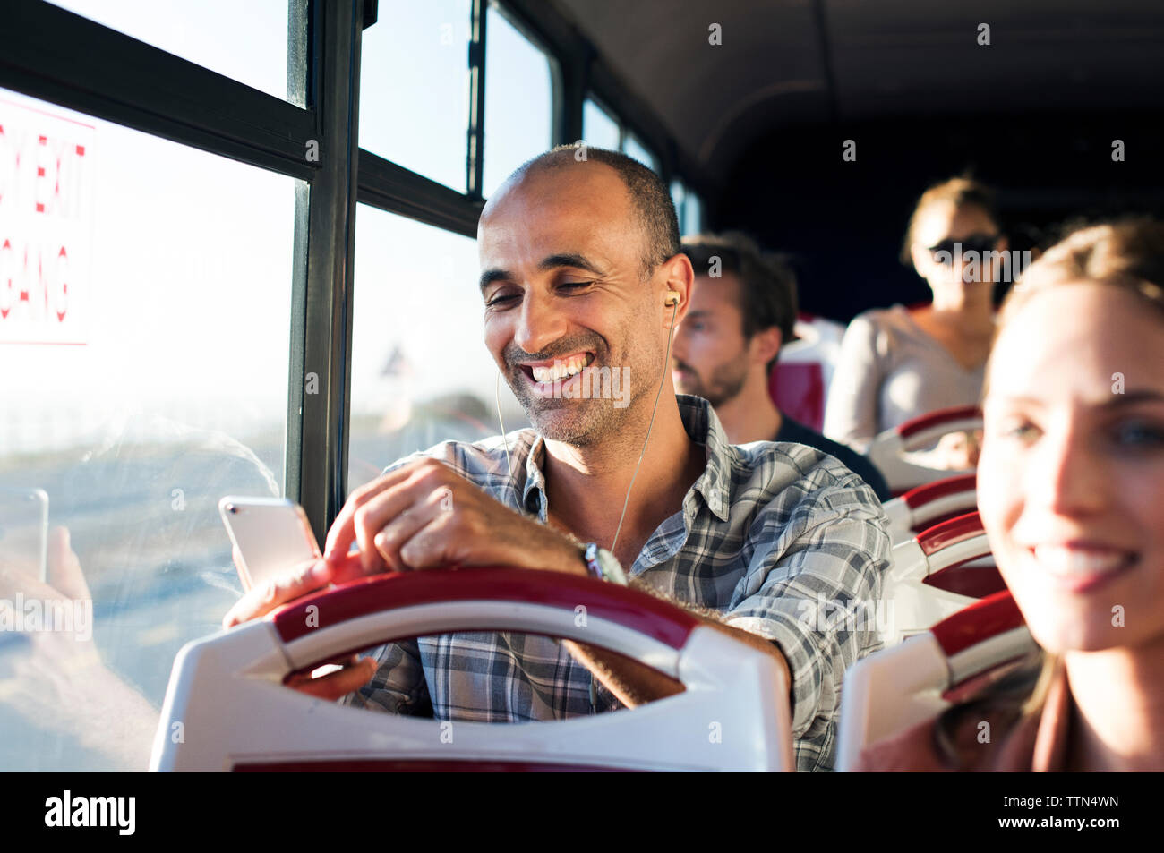 Glücklicher Mann mit Handy während der Fahrt im Reisebus Stockfoto