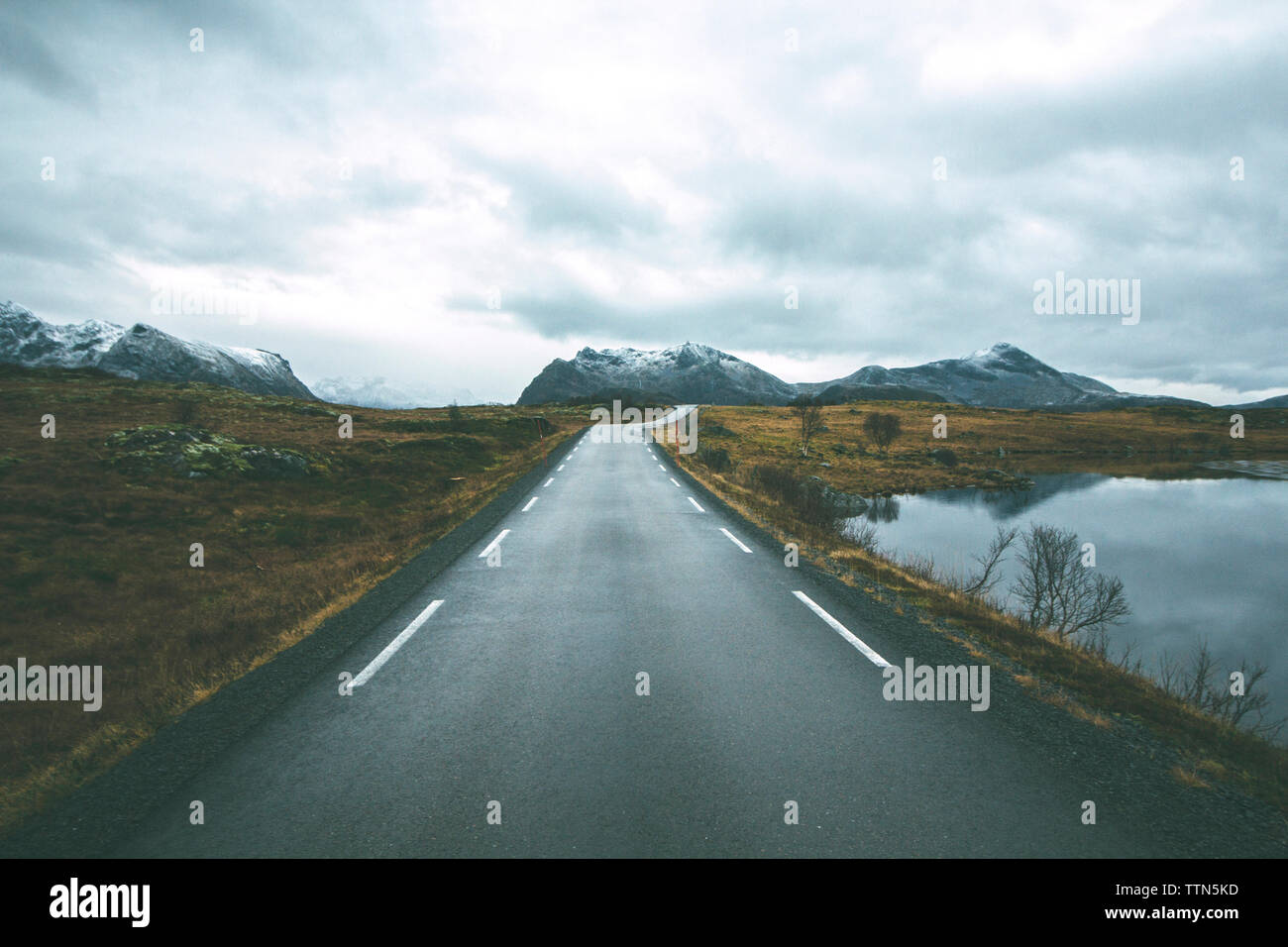Straße durch Feld gegen bewölkter Himmel im Winter Stockfoto