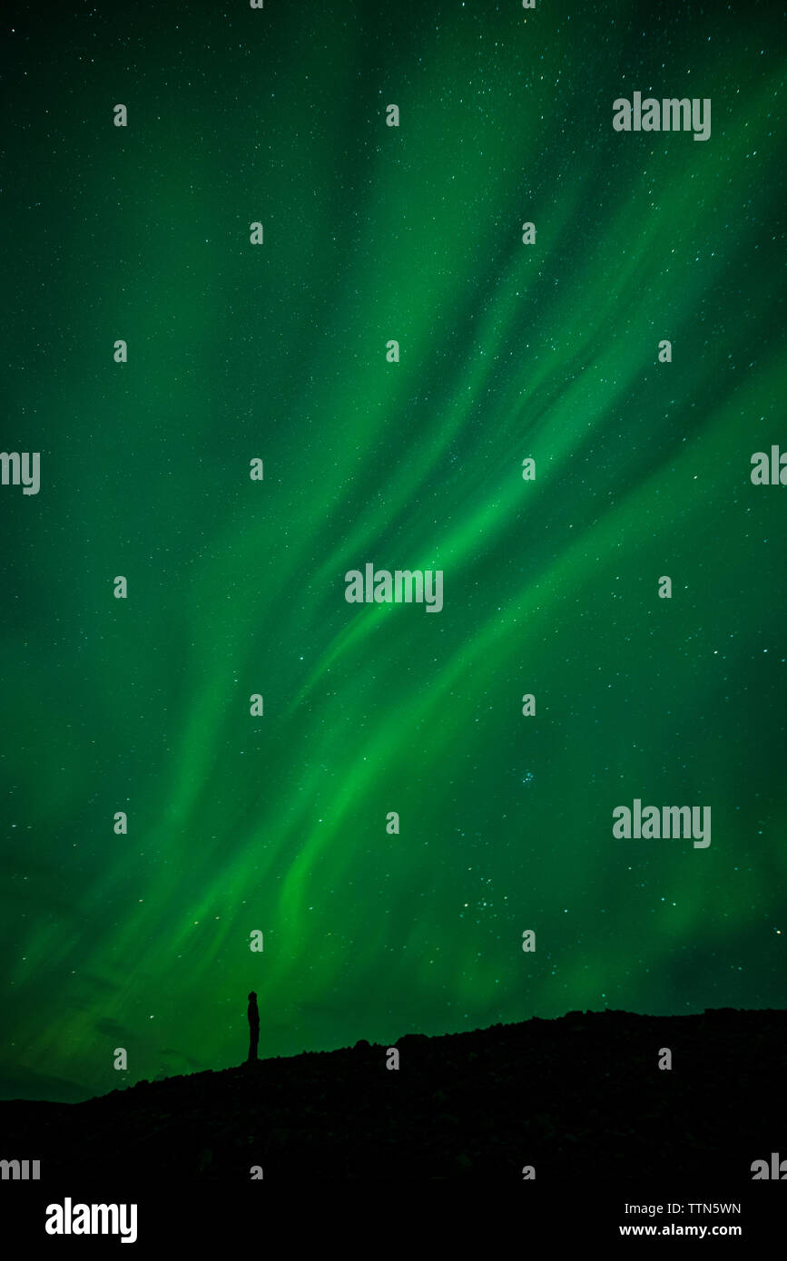 Silhouette Mann stand auf dem Feld gegen die Aurora Borealis Stockfoto