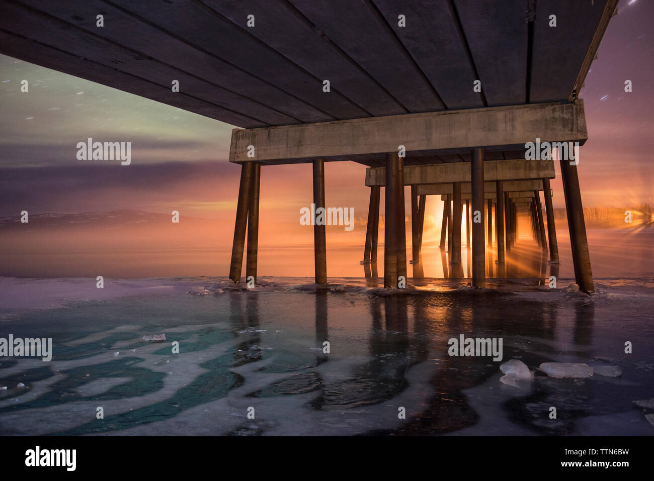 Low Angle View von Pier über gefrorene Meer bei Sonnenuntergang Stockfoto