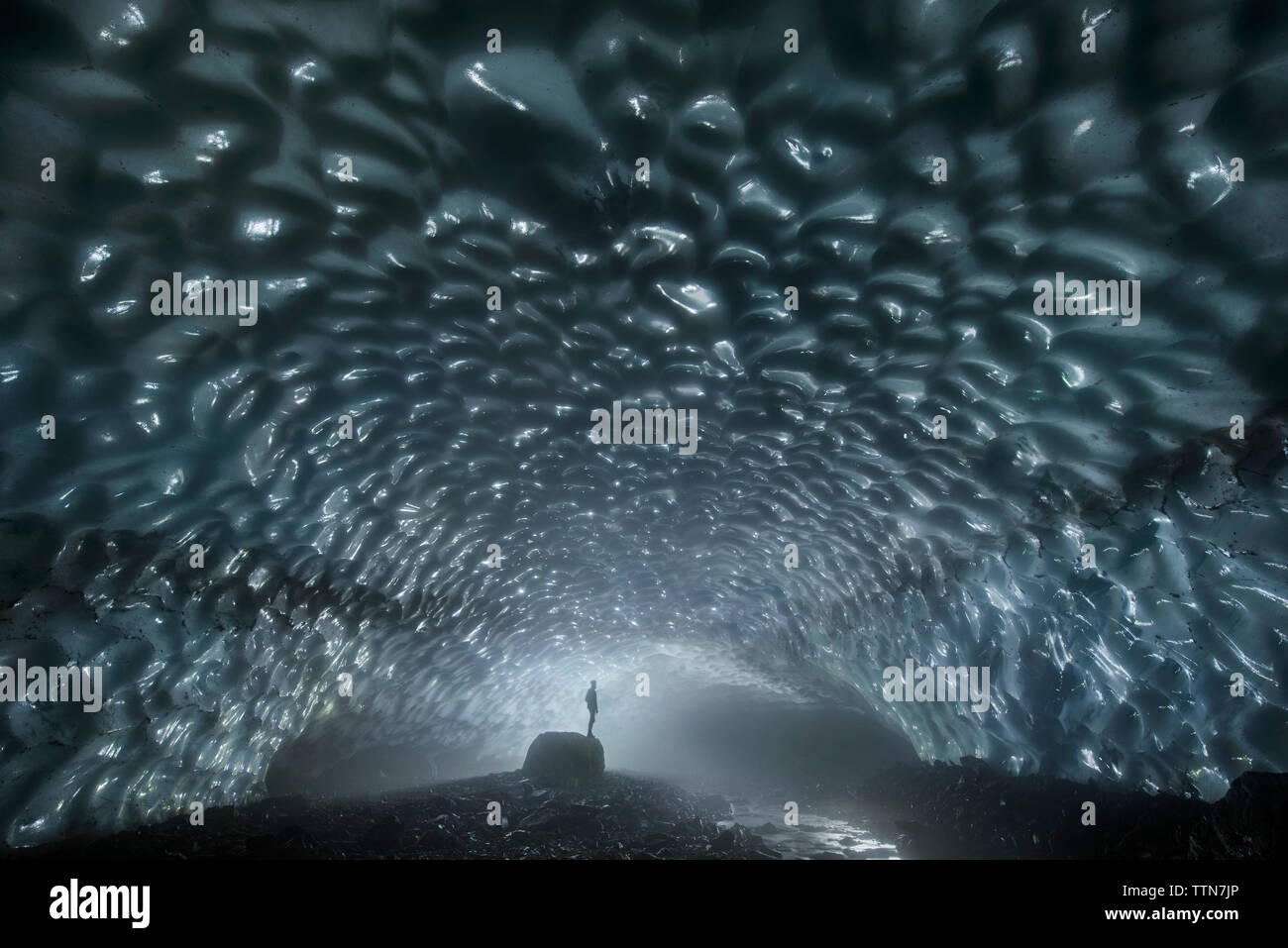 Silhouette Mann stand auf Felsen in der Eishöhle Stockfoto