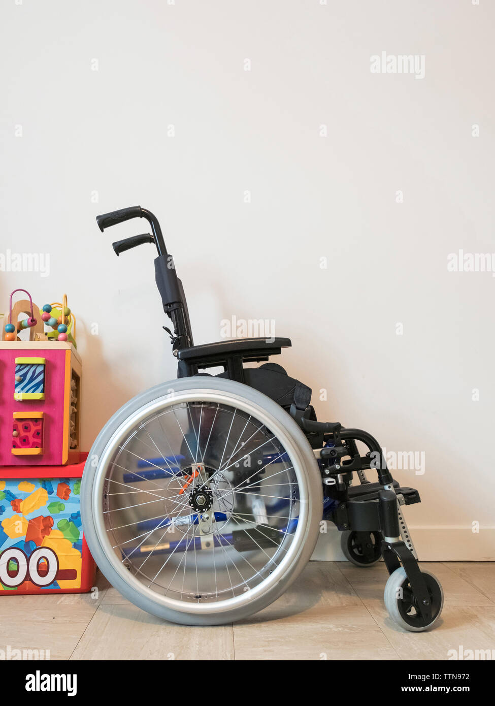 Leeren Rollstuhl durch Spielzeuge von Wand zu Hause Stockfoto