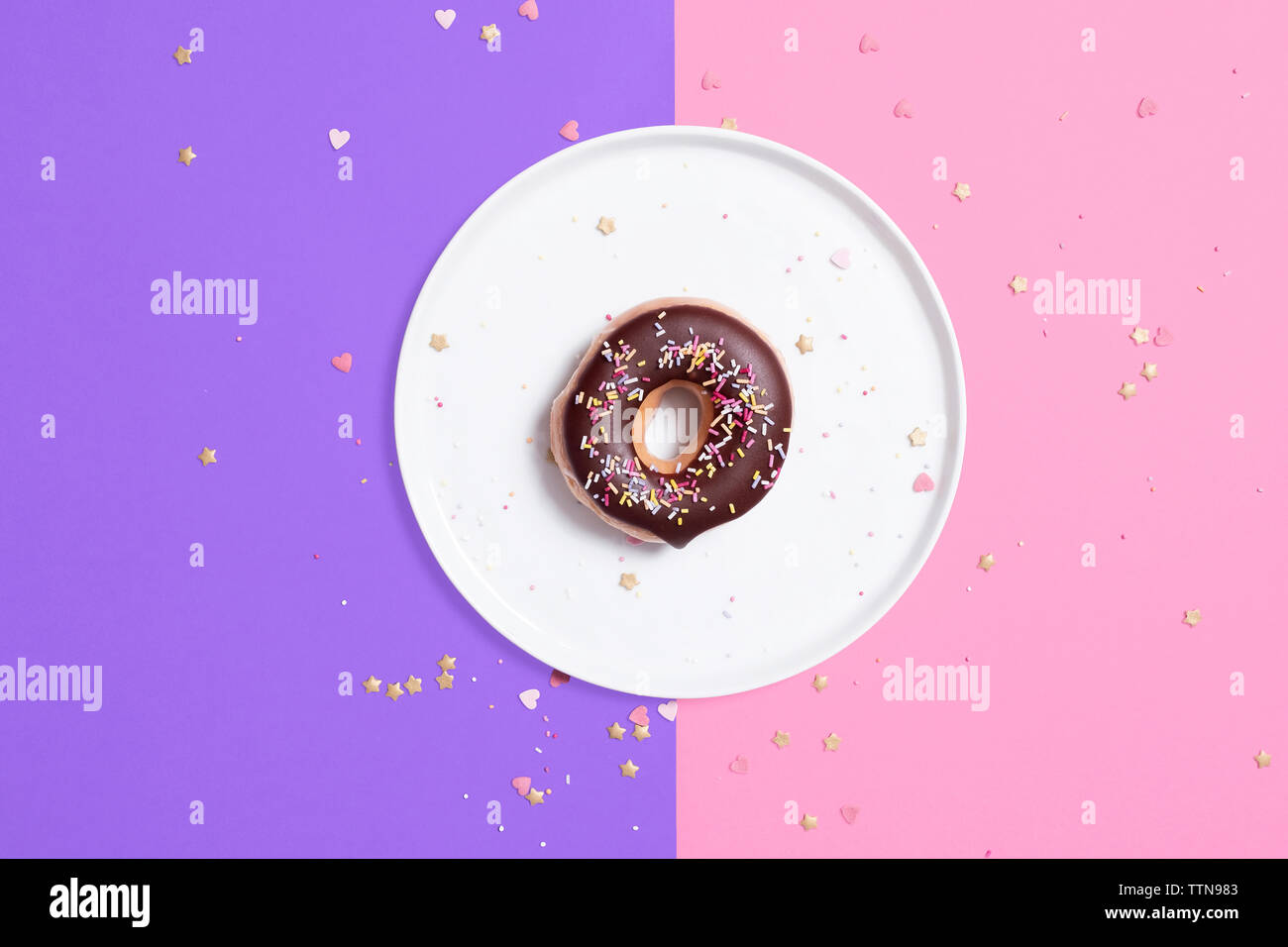 Ansicht von oben der Schokolade Donut in der Platte mit Konfetti auf farbigem Hintergrund Stockfoto