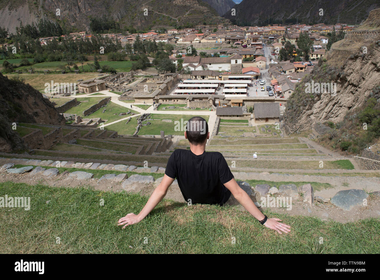 Ansicht der Rückseite des männlichen Wanderer Blick auf Dorf sitzend auf Schritte bei Pisac Stockfoto
