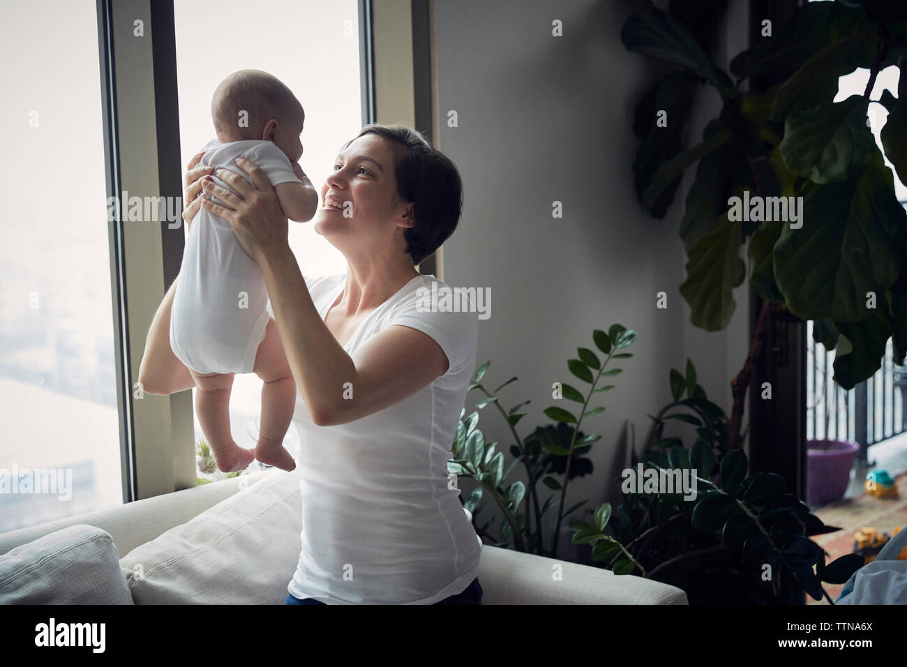 Glückliche Mutter spielt mit Sohn beim Sitzen auf dem Sofa zu Hause Stockfoto