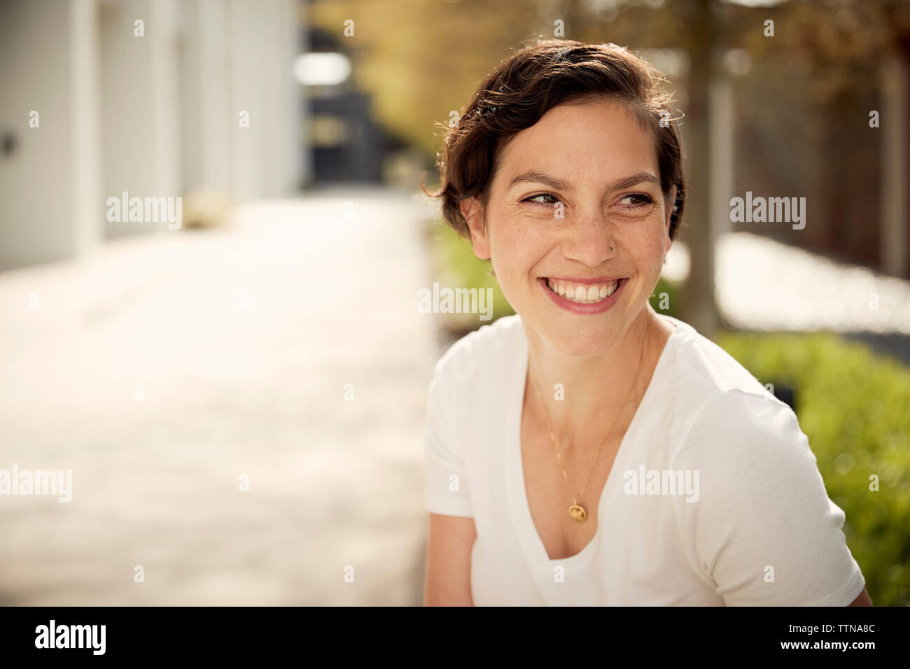 Nahaufnahme der glückliche Frau weg schauen beim Sitzen im Freien Stockfoto