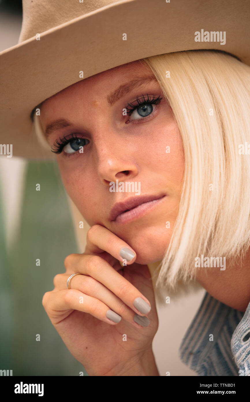 Close-up Portrait von selbstbewusste Frau mit der Hand am Kinn zu tragen hat während der Sitzung im Freien Stockfoto