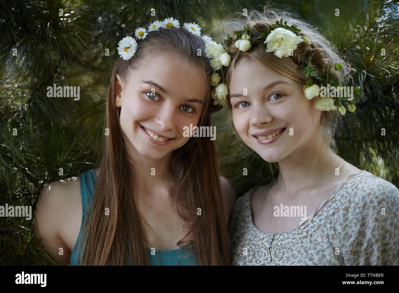 Portrait von glücklichen Freunde tragen tiaras während durch Pflanzen im Park stehende Stockfoto