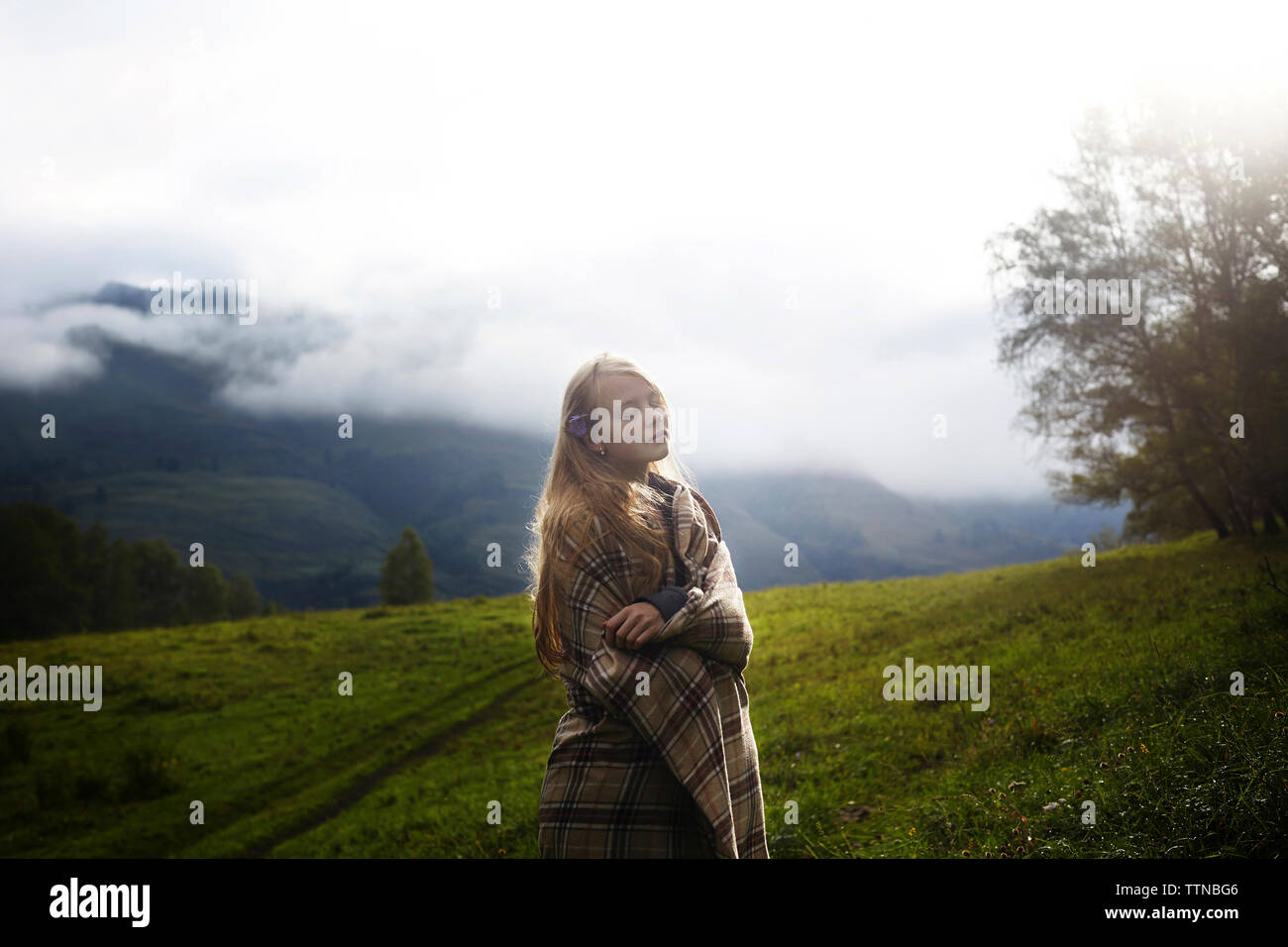 Frau, eingewickelt in eine Decke, die auf Feld Stockfoto