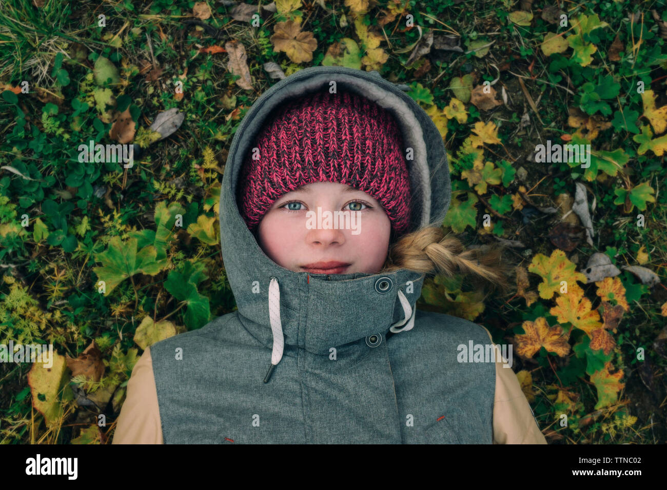 Junge Frau, die auf dem Gras in warme Kleidung Stockfoto