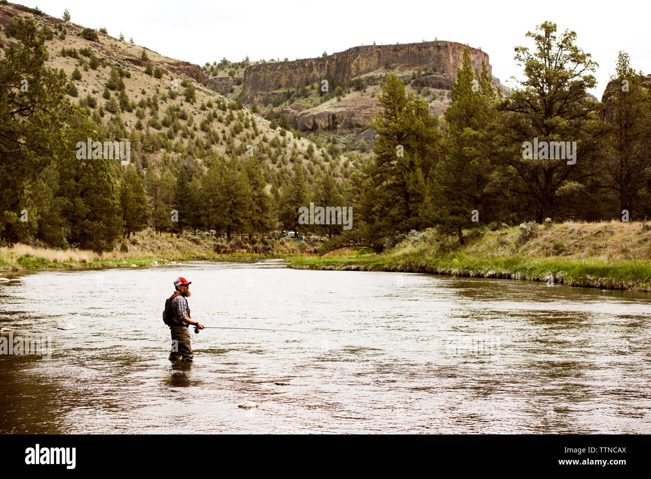 Seitenansicht des reifer Mann angeln im Fluss von Berg Stockfoto