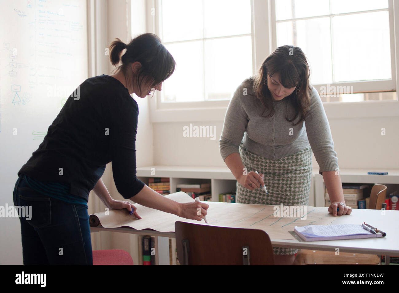 Geschäftsfrauen schreiben auf Papier am Schreibtisch in einem neuen Büro Stockfoto