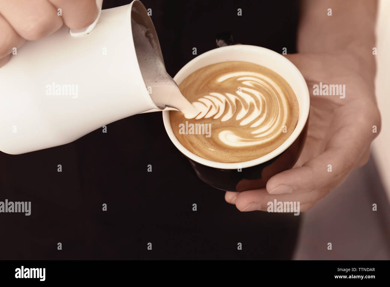 Mann Zeichnung auf Kaffee mit aufgeschäumter Milch Stockfoto