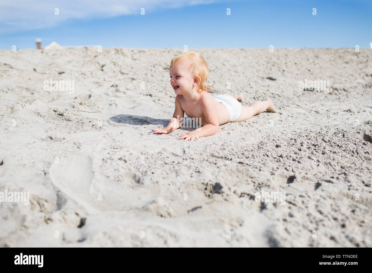 Blond kaukasischen Toddler lächelnd auf Sand Dune in ihrer Windel Stockfoto