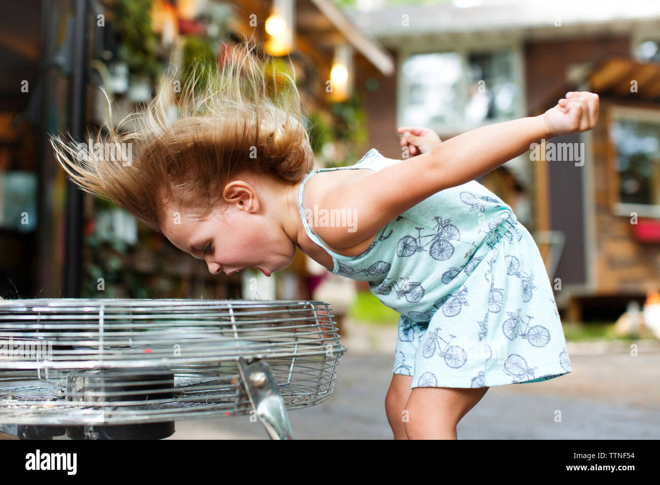 Mädchen schreien und genießen Brise von elektrischen Ventilator Stockfoto