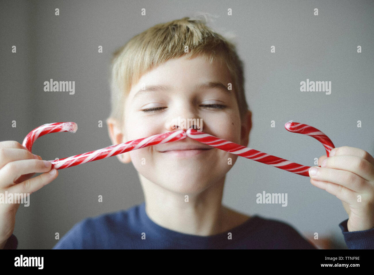 Verspielter Junge, Schnurrbart mit Zuckerstangen zu Hause Stockfoto