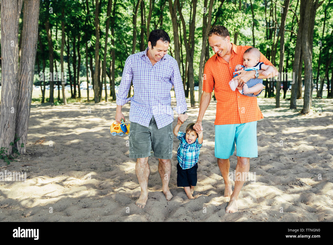Homosexuelle coupé Wandern mit Kindern am Strand. Stockfoto