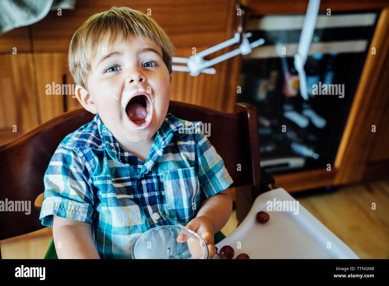 Portrait von Jungen in hohen Stuhl mit Mund Sitzung öffnen Stockfoto