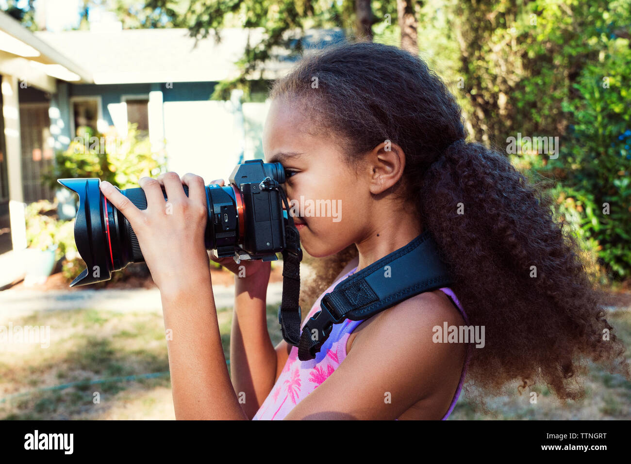 Seitliche Sicht auf Mädchen fotografieren mit der digitalen Kamera beim Stehen in Hof Stockfoto